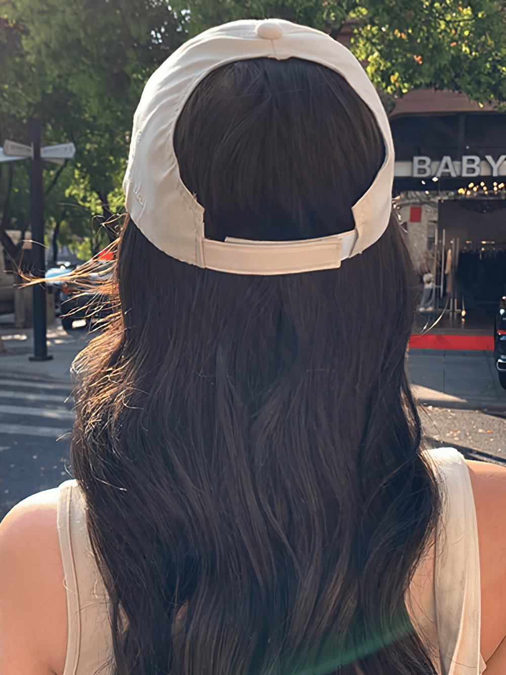 Person wearing a stylish adjustable cotton baseball cap with trendy letter pattern under the sun, showcasing its casual outing appeal.